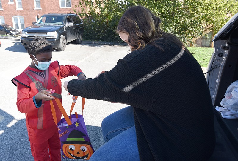 Staff Photo by Matt Hamilton / Teacher Sky Davis gives candy to Kenye Phillips, 10, a virtual learning student on Friday, Oct. 30, 2020, at First Baptist Church during a trunk or treat party in the church parking lot.
