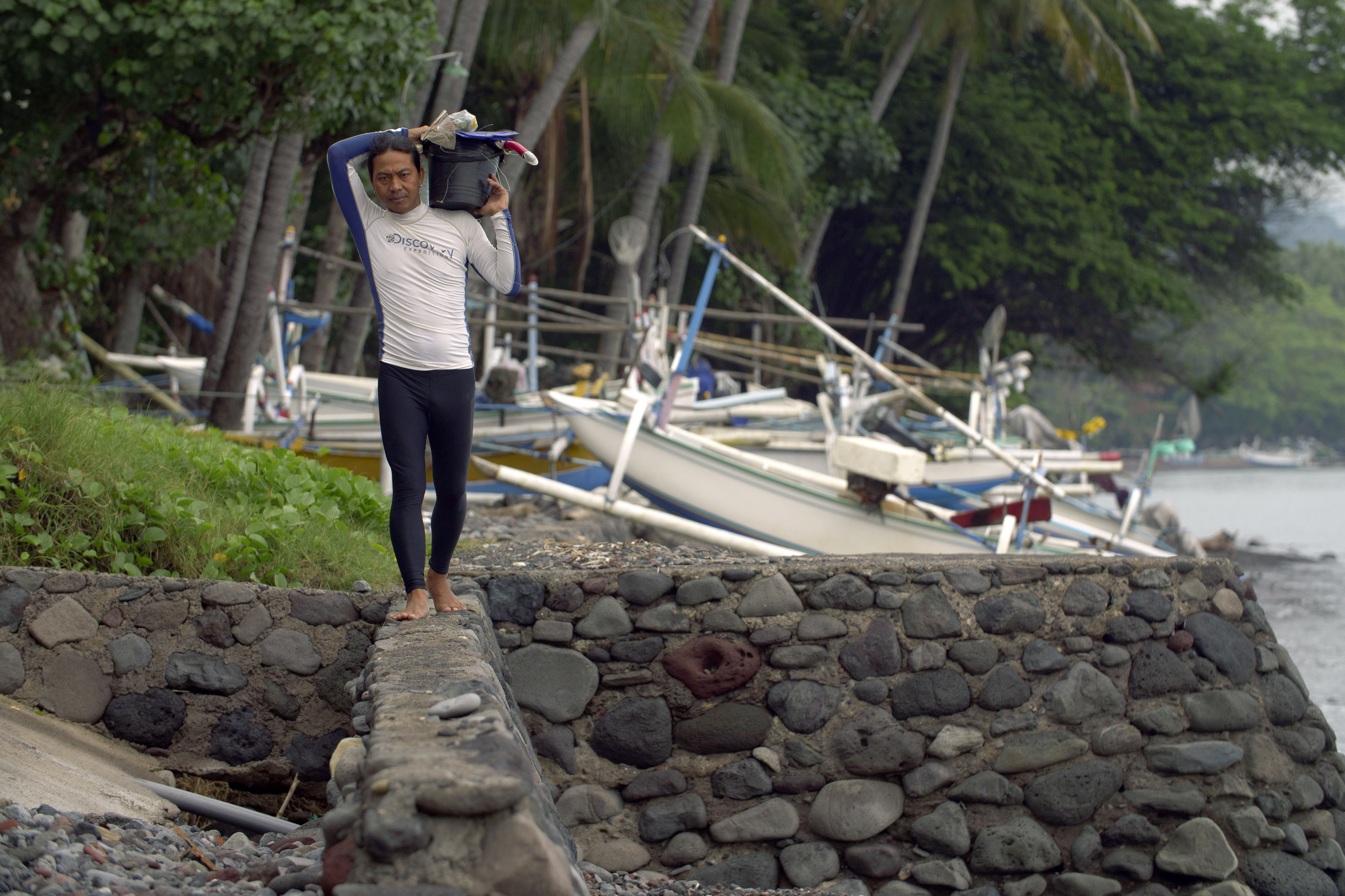 Made Partiana walks along beach area at Les, Bali, Indonesia, on April 11, 2021, as he prepares to catch aquarium fish. Over the years Partiana began to notice the reef was changing. “I saw the reef dying, turning black,†he says. “You could see there were less fish.†(AP Photo/Alex Lindbloom)