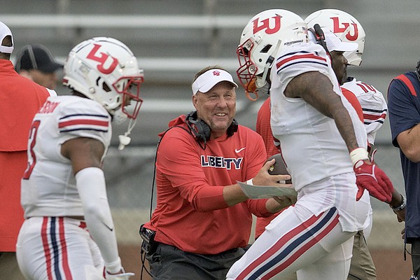 Liberty head coach Hugh Freeze smiles as Liberty defensive end Durrell Johnson (11) hands him a fumble recovery against Southern Miss during the first half of an NCAA football game on Friday, Sept. 3, 2022, in Hattiesburg, Miss. (AP Photo/Matthew Hinton)