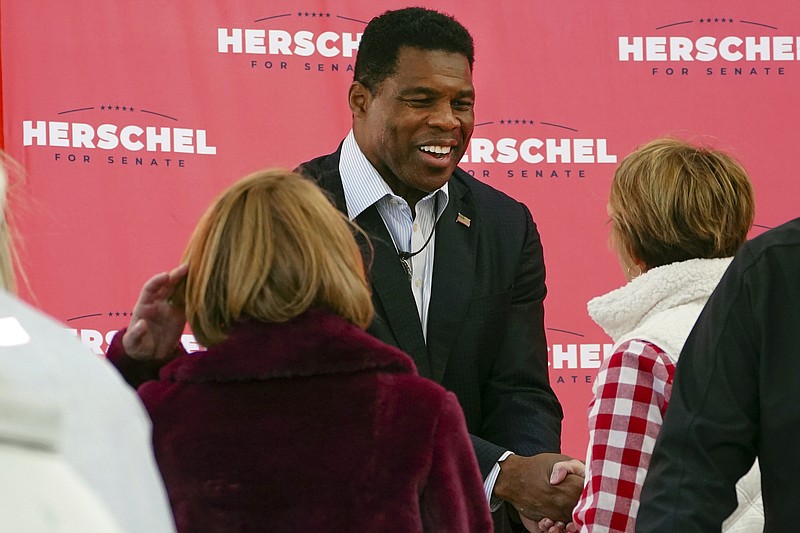FILE - Herschel Walker, Republican candidate for U.S. Senate in Georgia, greets supporters during a campaign rally Oct. 18, 2022, in Atlanta. Walker campaigns for the U.S. Senate as a champion of free enterprise and advocate for the mentally ill, felons and others. And the Georgia Republican has called for policies that blend those priorities. Yet Walker, through a major chicken processor that he touts as a principal partner to one of his primary businesses, Â has benefited from years of unpaid labor by drug offenders routed to the facility by Oklahoma state courts. (AP Photo/John Bazemore, File)