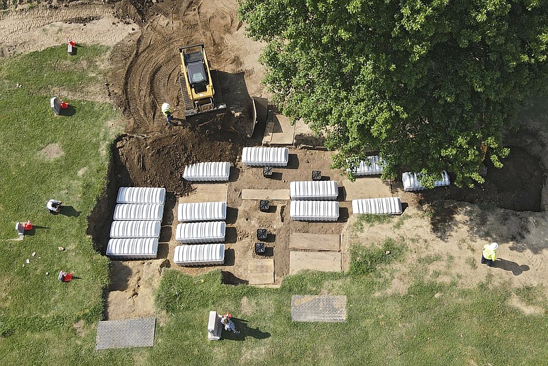 FILE - In this aerial photo, a mass grave is re-filled with dirt after a small ceremony at Oaklawn Cemetery on July 30, 2021, in Tulsa, Okla. The mass grave was discovered while searching for victims of the Tulsa Race Massacre. Some of the 19 bodies taken from the Tulsa cemetery that are possible victims of the 1921 Tulsa Race Massacre will be exhumed again starting Wednesday, Oct. 26, 2022, to gather more DNA for possible identification. (Mike Simons/Tulsa World via AP, File)