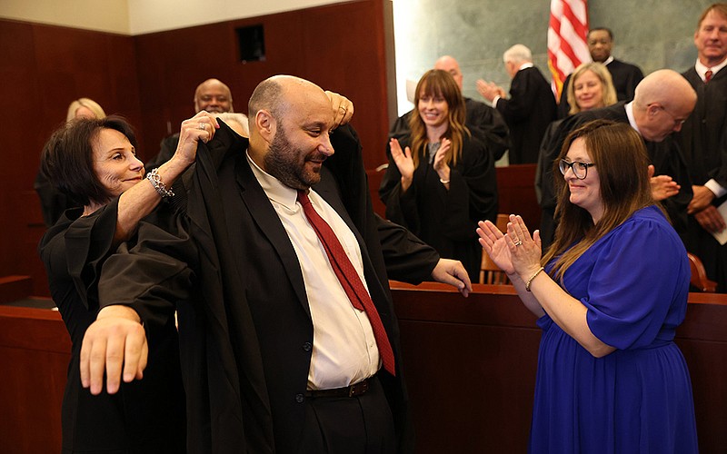 U.S. District Judge Lee Rudofsky gets help putting on his robes from his mother, Roselyn Rudofsky, while his wife, Soraya (right), applauds with others at his investiture ceremony Friday in Little Rock.
(Arkansas Democrat-Gazette/Colin Murphey)