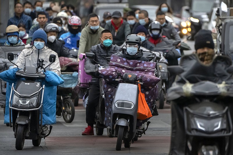 Commuters wearing masks ride scooters along a street Friday in the central business district in Beijing.
(AP/Mark Schiefelbein)