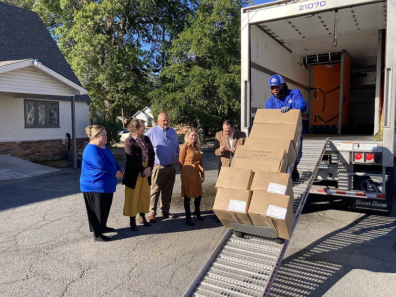 James McCann (right), a route service associate with Ben E. Keith Co., rolls boxes of frozen hams down a ramp and into Neighbor to Neighbor last week as part of a donation made possible through a partnership that includes two food companies and Saracen Casino Resort. Standing next to the truck (from left to right) are Kristi Strain with Petit Jean Meats; Pat Tate with Neighbor to Neighbor; Steve Coleman and Yvette Parker with Ben E. Keith Co.; and Carlton Saffa with Saracen Casino. 
(Pine Bluff Commercial/Byron Tate)