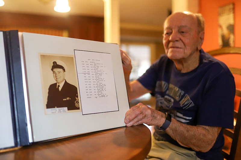 Staff photo by Olivia Ross / Thaddius Bartosz holds up a photo album with a picture of himself on Monday, October 31, 2022. Bartosz, who is 103 years of age, is a Navy Veteran.