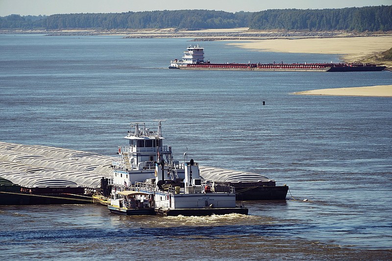 Low-water restrictions on the barge loads make for cautious navigation through the Mississippi River as evidenced by this tow passing a tow moored on the Louisiana-side bank of the river in Vicksburg, Tuesday, Oct. 11, 2022. The unusually low water level in the lower Mississippi River is causing some barges to get stuck in the muddy river bottom, resulting in delays. (AP Photo/Rogelio V. Solis)