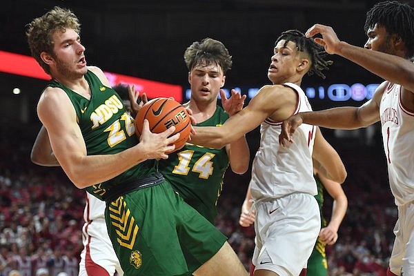 Arkansas forward Trevon Brazile (1) reaches to collect a rebound Monday, Nov. 7, 2022, as North Dakota State forward Joshua Streit (22) and guard Boden Skunberg (14) take control of the ball during the first half of play in Bud Walton Arena in Fayetteville.