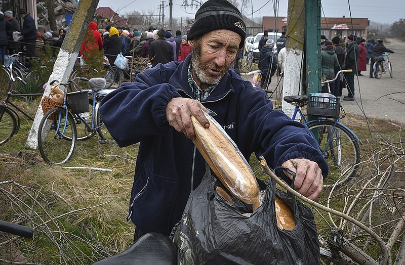 Residents receive bread Wednesday in the recently recaptured village of Yampil in eastern Ukraine. Villages and towns were hit by more heavy fighting and shelling Wednesday as Ukrainian and Russian forces strained to advance on different fronts. More photos at arkansasonline.com/ukrainemonth9/.
(AP/Andriy Andriyenko)