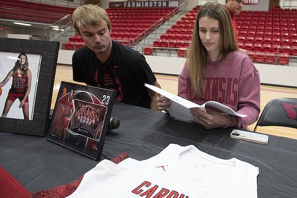 Farmington basketball player Jenna Lawrence (right) and her brother Gabe Lawrence look through paperwork as she signs a national letter of intent to play for the Arkansas Razorbacks on Wednesday, Nov. 9, 2022, in Farmington.