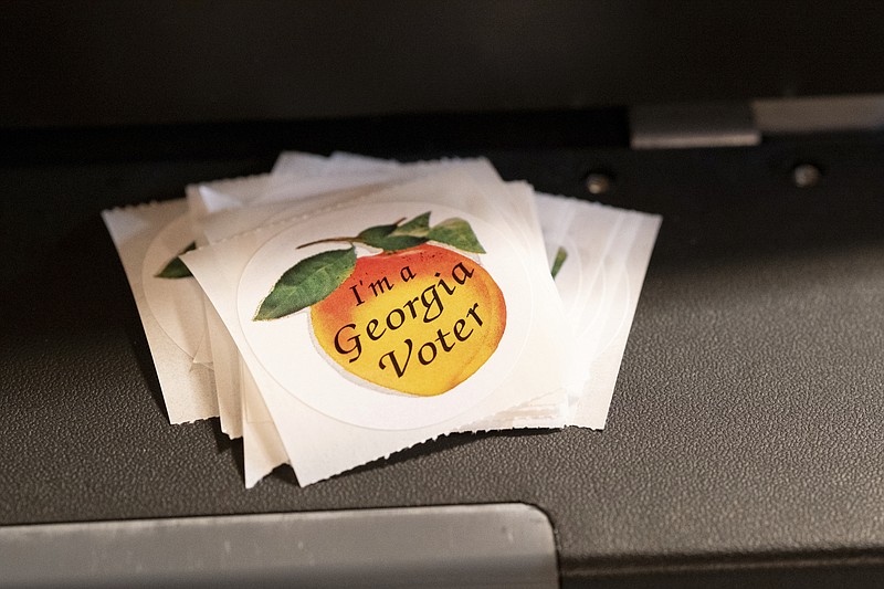 A stack of stickers sits atop the ballot scanner during the mid-term election Tuesday, Nov. 8, 2022 at Lawrenceville Road United Methodist Church in Tucker, Ga. (AP Photo/Ben Gray)