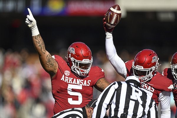 Arkansas defensive linemen Cameron Ball (5) and Dorian Gerald (23) celebrate a fumble recovery by teammate Latavious Brini during a game against LSU on Saturday, Nov. 12, 2022, in Fayetteville.