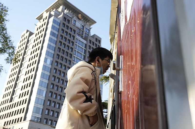 A man gets swabbed for COVID test near a building of the Peking University in Beijing, Wednesday, Nov. 16, 2022. Chinese authorities locked down the major university in Beijing on Wednesday after finding one COVID-19 case as they stick to a "zero-COVID" approach despite growing public discontent. (AP Photo/Ng Han Guan)