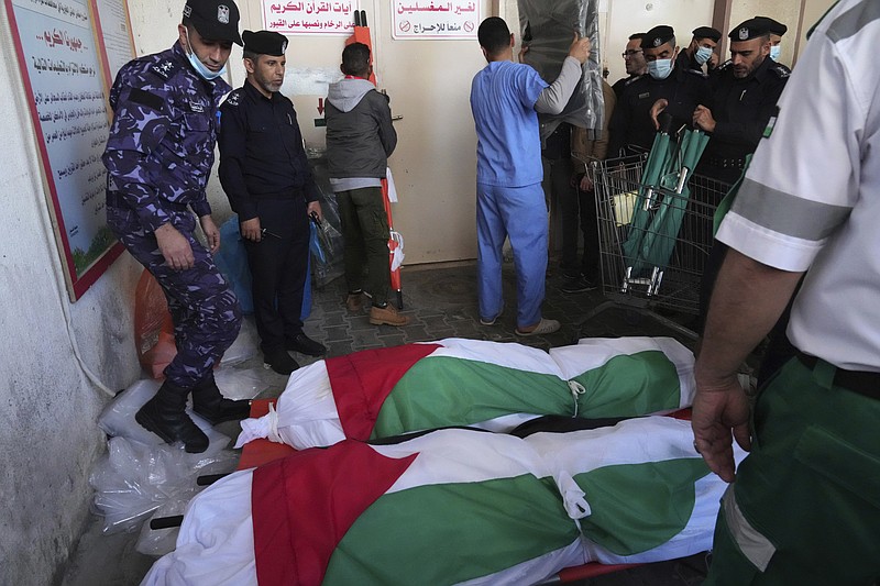Hamas police officers and medics stand near two bodies of 21 bodies from the Abu Raya family who were killed in a fire, at the morgue of the hospital during their funeral in Jebaliya refugee camp, northern Gaza Strip, Friday, Nov. 18, 2022. A fire set off by stored gasoline in a residential building killed 21 people Thursday evening in a refugee camp in the northern Gaza Strip, the territory's Hamas rulers said, in one of the deadliest incidents in recent years outside the violence stemming from the Israeli-Palestinian conflict. (AP Photo/Adel Hana)