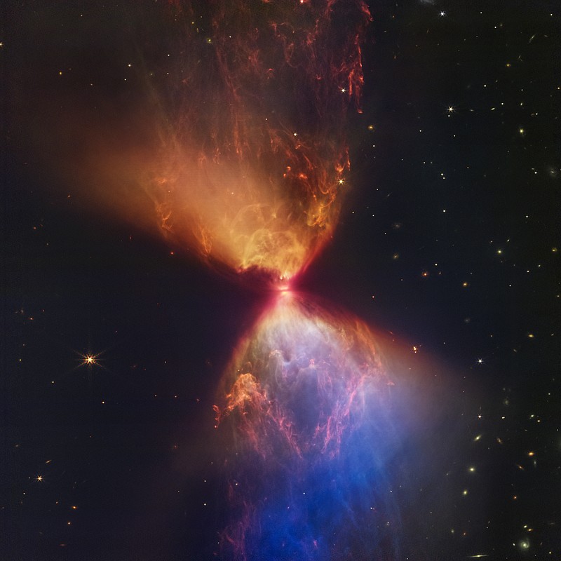 This image made available by the Space Telescope Science Institute on Wednesday, Nov. 16, 2022, shows a protostar within the dark cloud L1527 embedded within a cloud of material feeding its growth, captured by the James Webb Space Telescope. Ejections from the star have cleared out cavities above and below it, whose boundaries glow orange and blue in this infrared view. The region at lower right appears blue, as there's less dust between it and Webb than the orange regions above it. (NASA, ESA, CSA, STScI, Joseph DePasquale (STScI), Alyssa Pagan (STScI), Anton M. Koekemoer (STScI) via AP)