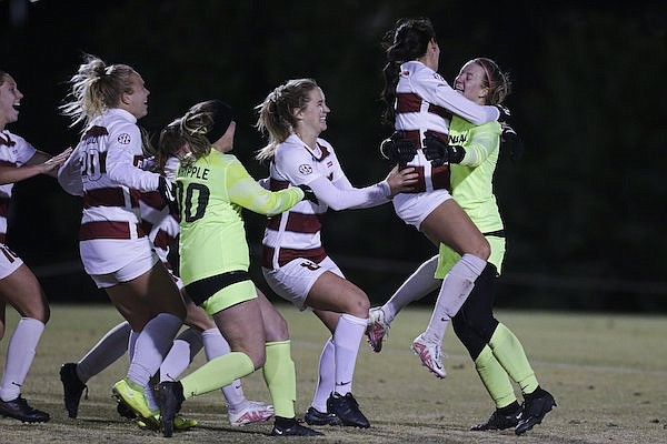 Arkansas goalkeeper Grace Barbara (right) is swarmed by teammates after she recorded the last of her three saves during a penalty shootout Sunday, Nov. 20, 2022, in Fayetteville. The Razorbacks defeated Memphis 3-2 in the shootout to advance to the quarterfinals of the NCAA Tournament.