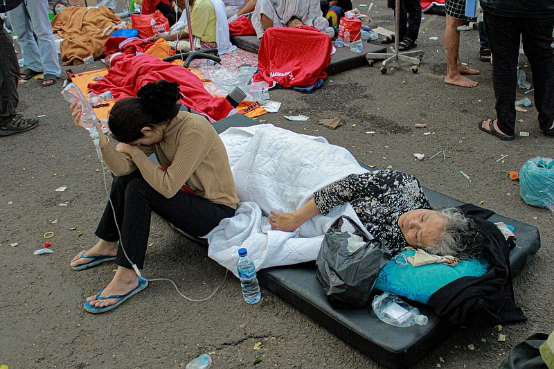 Earthquake survivors are treated outside of a hospital in Cianjur, West Java, Indonesia, Monday, Nov. 21, 2022. An earthquake shook Indonesia's main island of Java on Monday damaging dozens of buildings and sending residents into the capital's streets for safety. (AP Photo/Kholid)