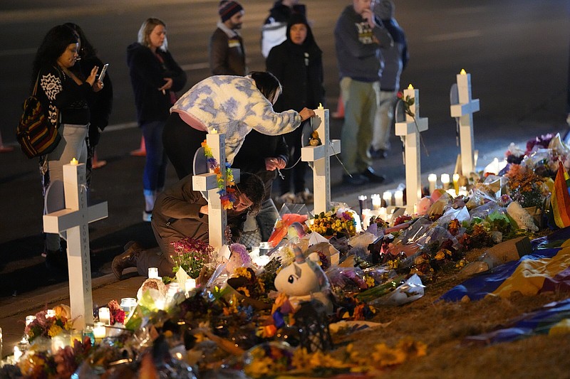 People sign the crosses of victims during a candlelight vigil on a corner near the site of a weekend mass shooting at a gay bar, late Monday, Nov. 21, 2022, in Colorado Springs, Colo. (AP Photo/Jack Dempsey)