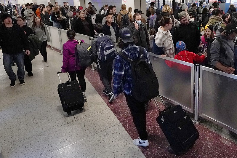 Travelers wheel the bags past the line for TSA screening in Terminal B at Logan International Airport, Monday, Nov. 21, 2022, in Boston. Travel experts say the ability of many people to work remotely is letting them take off early for Thanksgiving or return home later. Crowds are expected to rival those of 2019, the last Thanksgiving before the pandemic. (AP Photo/Charles Krupa)