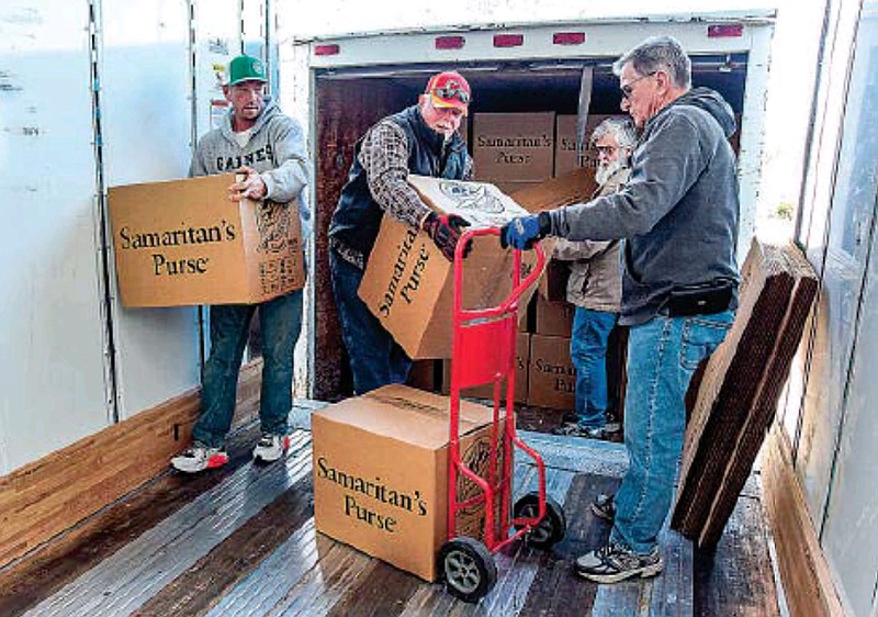 Steve Thompson, at left, carries a case to be counted Monday, Nov. 21, 2022, while Tommy Roam, middle, and Bob Krattli stack boxes on a dolly to be moved to the front of the trailer for counting and stacking. (Julie Smith/News Tribune photo)