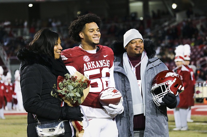 Arkansas defensive lineman Zach Williams (center) takes part in senior night activities last Saturday in Fayetteville with his mother Keli and his father Rickey, a former Razorback. Friday’s game at Missouri will be just one of a long list of road trips for the Williams and other Razorback parents.
(NWA Democrat-Gazette/Charlie Kaijo)