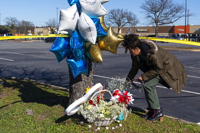 Shyleana Sausedo-Day, from Portsmouth, Va., places flowers near the scene of a mass shooting at a Walmart, Wednesday, Nov. 23, 2022, in Chesapeake, Va. A Walmart manager opened fire on fellow employees in the break room of the Virginia store, killing several people in the countryâ€™s second high-profile mass shooting in four days, police and witnesses said Wednesday.  (AP Photo/Alex Brandon)