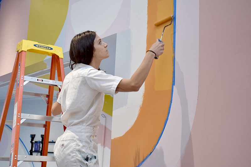 Rachel Dickerson/The Weekly Vista Paige Dirksen of Bella Vista works on a mural titled "Whimsy" that she is creating at the Bella Vista Public Library in the children's wing.