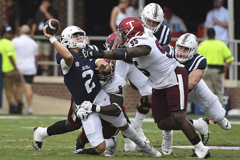 Mississippi quarterback Jaxson Dart (left) releases a pass under pressure from Troy linebacker Richard Jibunor (9) and defensive tackle Luis Medina (95) earlier this season. Troy can become the Sun Belt Conference West Division champions with a victory today over Arkansas State.
(AP/Thomas Graning)