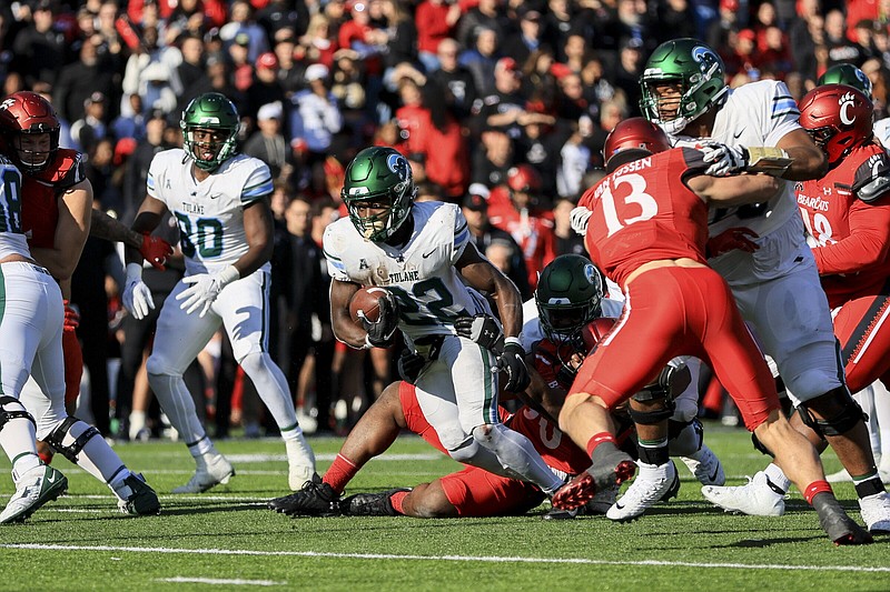 Tulane running back Tyjae Spears (center) stiff-arms Cincinnati safety Ja’von Hicks on his way to a touchdown during the first half Friday in Cincinnati. Spears rushed for 181 yards and two scores in a 27-24 victory as Tulane beat Cincinnati for the first time in five tries.
(AP/Aaron Doster)