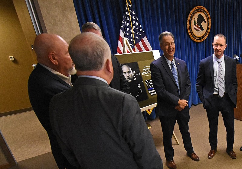 A photo of the late Pine Bluff Detective Kevin Collins (center) is visible in the center of the room at the U.S. attorney’s office in Little Rock in this Nov. 9, 2022 file photo. Representatives from law enforcement agencies across the state were talking before a news conference to announce the indictments of 80 people in central Arkansas. The officials said the indictments were the culmination of investigative work done by Collins, who was shot to death on Oct. 5, 2020. (Arkansas Democrat-Gazette/Staci Vandagriff)