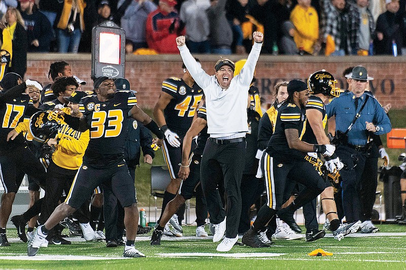 Missouri coach Eli Drinkwitz leaps as players run onto the field after the final play in Friday’s 29-27 win against Arkansas at Faurot Field in Columbia. (Associated Press)