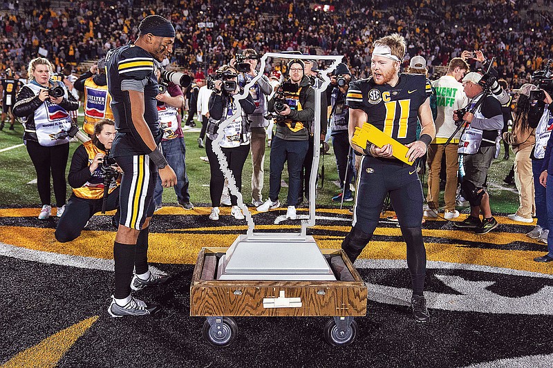 Missouri teammates Tauskie Dove (left) and Barrett Banister look at the Battle Line Trophy after the Tigers defeated Arkansas 29-27 on Friday at Faurot Field in Columbia. (Associated Press)
