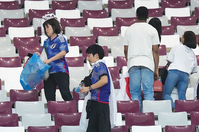 Japan supporters clean the stands last Wednesday at the end of the World Cup Group E match against Germany in Doha, Qatar. (Associated Press)
