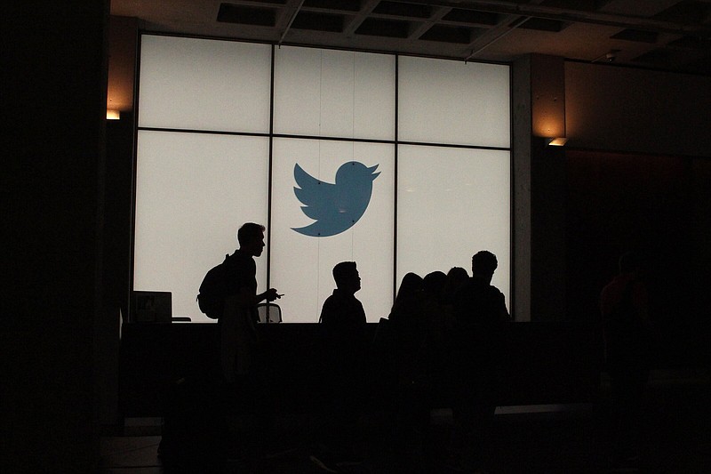 Employees walk past a lighted Twitter logo as they leave the company’s headquarters in San Francisco in this file photo. 
(Getty Images/TNS)