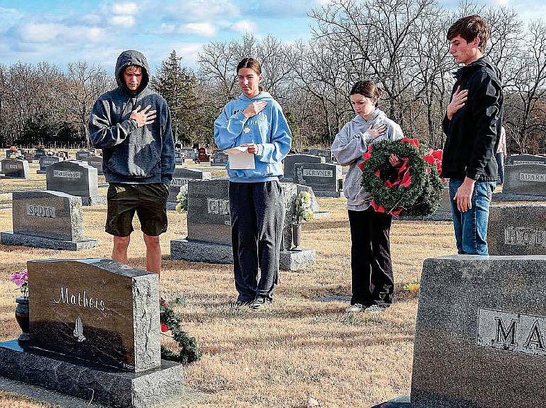 After placing a wreath at this veteran's grave, Ron Bocklage, Amanda Moulton, Kamryn Henggeler and Logan Kleist stand with hand over heart and pause for a moment of silence Tuesday, Nov. 29, 2022, at Enloe Cemetery in Russellville, Mo. (Julie Smith/News Tribune photo)