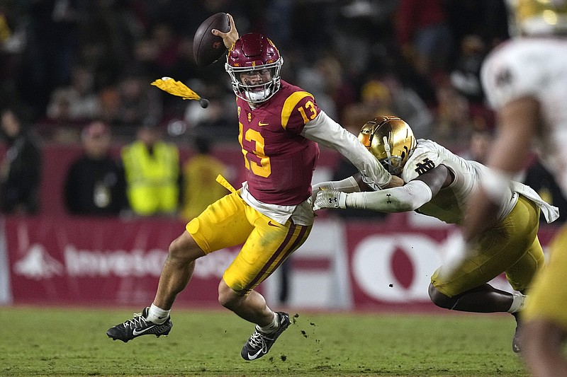 Southern California quarterback Caleb Williams, left, escapes a tackle by Notre Dame defensive lineman Justin Ademilola as a flag is thrown on the play during the second half of an NCAA college football game Saturday, Nov. 26, 2022, in Los Angeles. (AP Photo/Mark J. Terrill)