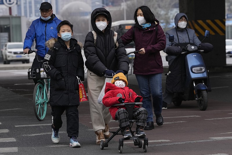 A family walks across the street Friday in Beijing.
(AP/Ng Han Guan)
