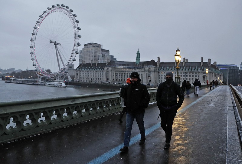 FILE - Commuters walk through light snowfall on Westminster Bridge as temperatures dropped below freezing in London, Tuesday, Feb. 9, 2021. (AP Photo/Frank Augstein, File)