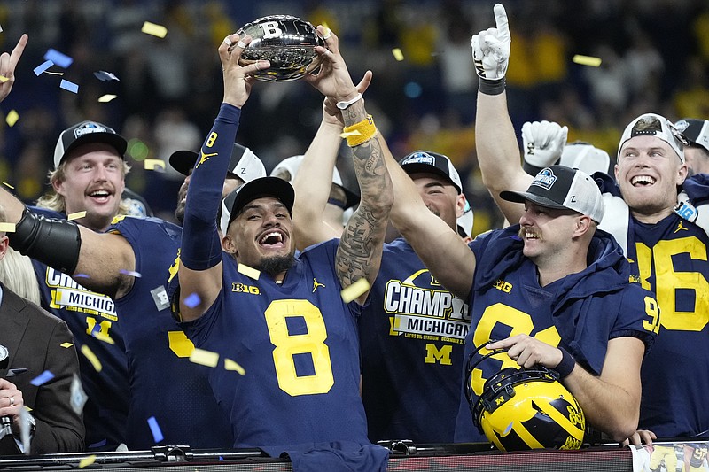 AP photo by AJ Mast / Michigan wide receiver Ronnie Bell holds the Big Ten championship trophy as he celebrates with teammates after the Wolverines defeated Purdue in the conference title game Saturday night in Indianapolis.