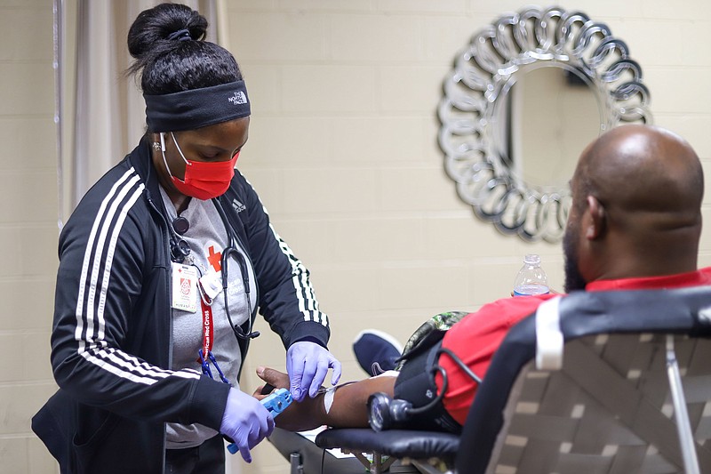 Staff photo by Olivia Ross  / LaTasha Lavender assists as Michael Logan donates blood Thursday at Orchard Park Seventh-day Adventist Church. The church's pastor, Troy Brand, works to educate and encourage more Black Chattanoogans to donate blood for patients with sickle cell disease.