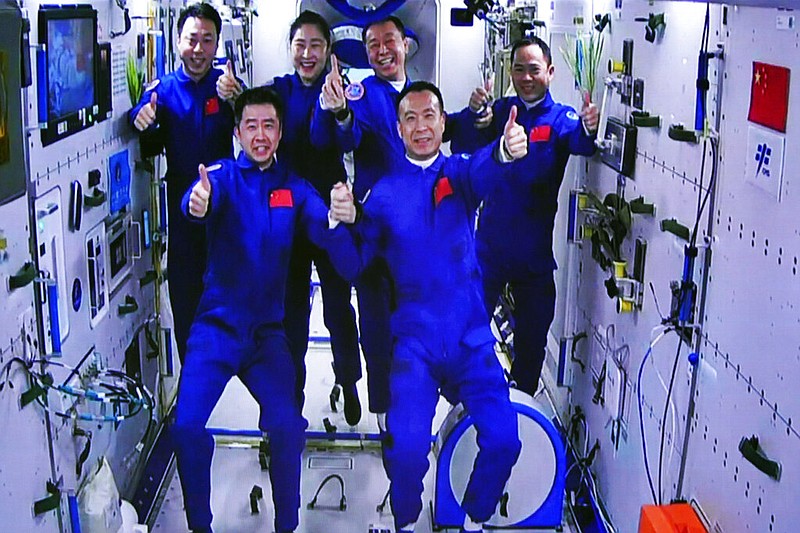 In this photo released by Xinhua News Agency, an image captured off a screen at the Jiuquan Satellite Launch Center in northwest China shows the Shenzhou-15 and Shenzhou-14 crew taking a group picture with their thumbs up after a historic gathering in space on Wednesday, Nov. 30, 2022. (Guo Zhongzheng/Xinhua via AP)