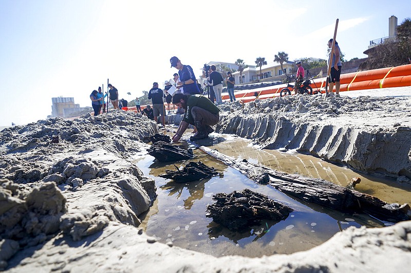 Members of a team of archaeologists study a wooden structure in the sand, Tuesday, Dec. 6, 2022, in Daytona Beach, Fla. Severe beach erosion caused by two late-season hurricanes helped partially uncover what appears to be part of an 80-foot-long (24-meters) ship in the sand on Daytona Beach Shores, officials said. (AP Photo/John Raoux)