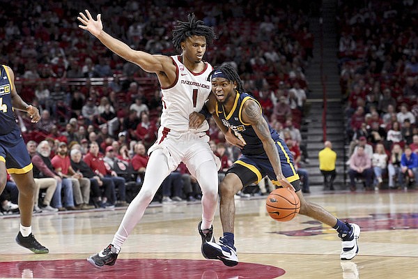 UNC Greensboro guard Kobe Langley (3) drives against Arkansas guard Ricky Council (1) during the first half of an NCAA college basketball game Tuesday, Dec. 6, 2022, in Fayetteville. (AP Photo/Michael Woods)