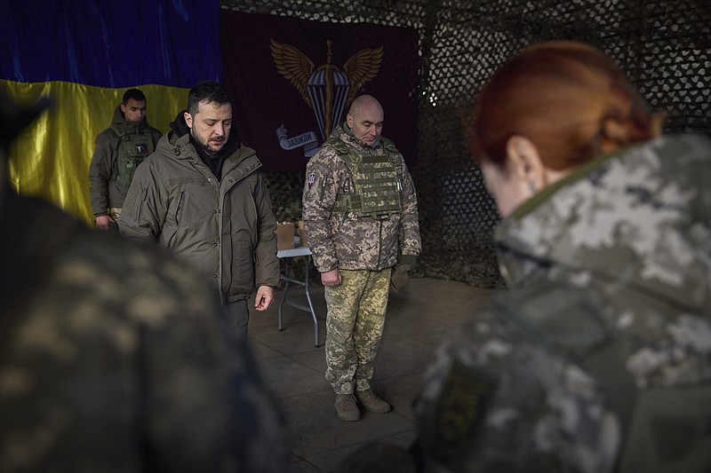 In this photo provided by the Ukrainian Presidential Press Office, Ukrainian President Volodymyr Zelenskyy, centre left, stands along servicemen during a minute of silence in honor of soldiers killed during fighting with Russian troops as he visits the Sloviansk, Donbas region, Ukraine, Tuesday, Dec. 6, 2022. (Ukrainian Presidential Press Office via AP)