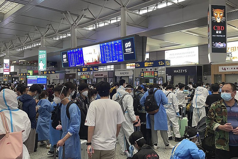 In this photo taken May 2022 and released by Leah Zhang, passengers some wearing protective overalls wait for their train at a train station in Shanghai. Over 26 million people in Shanghai were confined for two months in one of the country's strictest and most visible lockdowns. (Leah Zhang via AP)