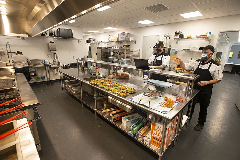 Caleb Meehan, (right) sous chef at the Fayetteville Public Library’s teaching kitchen, and Matt Eiler, manager of food service, work Monday Jan. 3, 2022 in the kitchen.  (NWA Democrat-Gazette/J.T. Wampler)