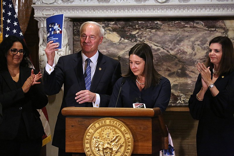 Gov. Asa Hutchinson holds up the 2022 Arkansas Women’s Commission Report after it was presented by his chief of staff, Alison Williams, during a press conference on Wednesday at the state Capitol in Little Rock.
(Arkansas Democrat-Gazette/Thomas Metthe)