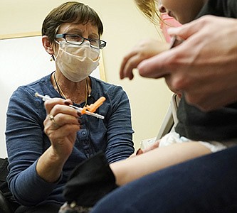Nurse Deborah Sampson gives a 20-month-old child a regular covid-19 shot in Seattle in June.
(AP/Ted S. Warren)