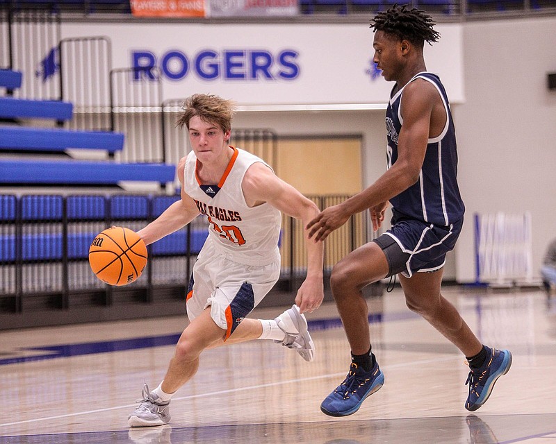 Rogers Heritage War Eagles Senior Parker Branscum (20) drives past Lee Summit West Titans Junior Chaz Watson (0) during the boys basketball game between Rogers Heritage and Lee’s Summit (Mo.) West during the Arvest Hoopfest, December 8, 2022, at the Rogers High School Gym, Rogers, Arkansas (Special to NWA Democrat-Gazette/Brent Soule)