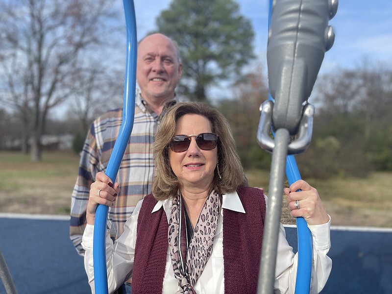 On Friday, Dec 9, 2022, Diana Smith, with her husband, Lonnie Smith standing behind her, sits on one of the swings at a new inclusive playground at Faith United Methodist Church on W. Markham Street in Little Rock. The new playground, which was dedicated on Dec. 9, was given by the congregation to the community in memory of Smith's aunt, Rebecca Lay.