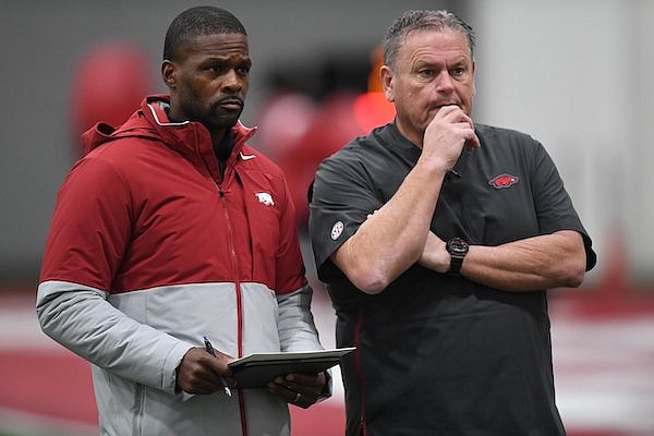 Arkansas defense coordinator Travis Williams (left) speaks Monday, Dec. 19, 2022, with coach Sam Pittman during practice inside the Walker Pavilion on the university campus in Fayetteville.